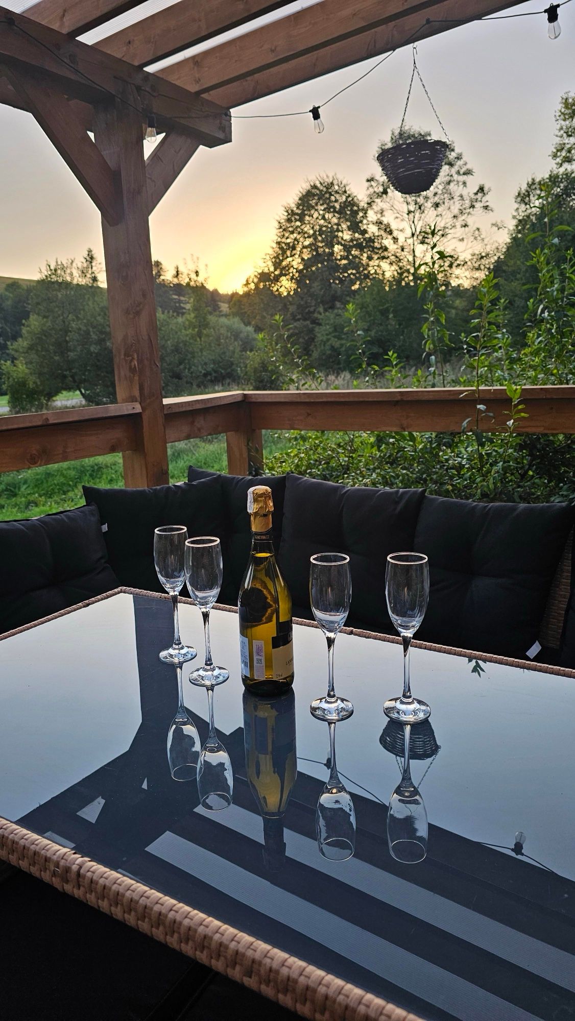 Prosecco i kieliszki na tarasie pod pergolą o zachodzie słońca